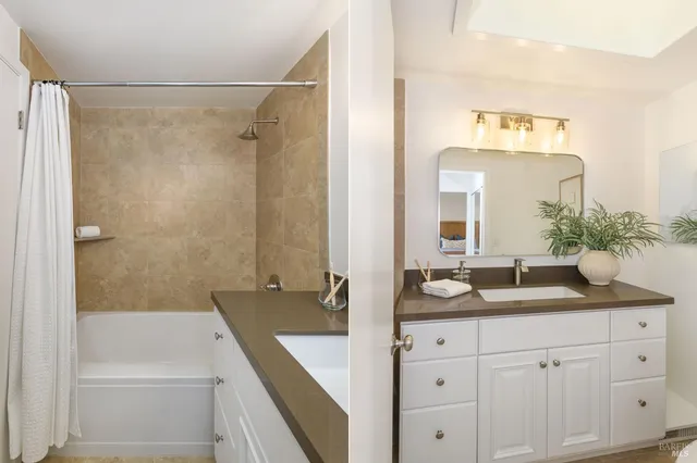 a bathroom with a granite countertop sink mirror and a bathtub