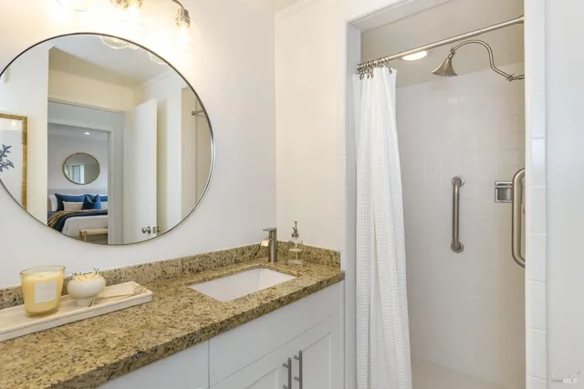 a bathroom with a granite countertop sink mirror and shower