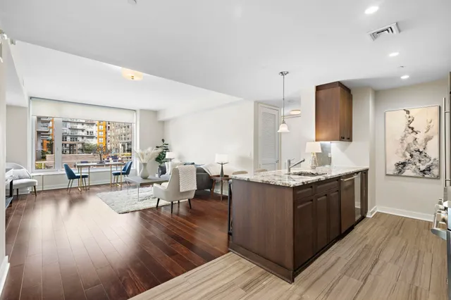 a large white kitchen with wooden floor and stainless steel appliances