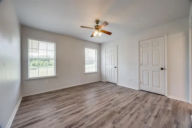 an empty room with wooden floor ceiling fan and window