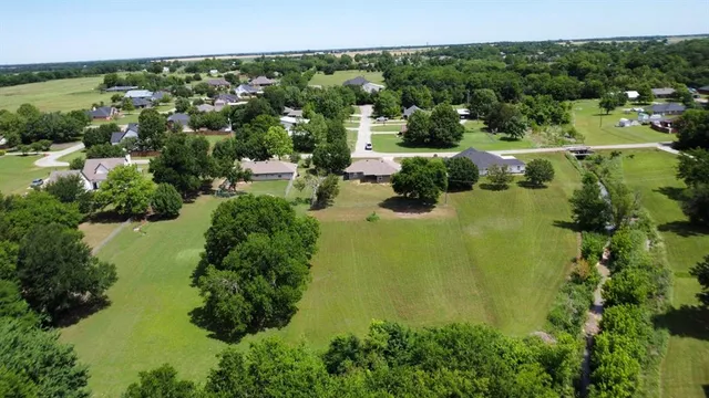 an aerial view of residential houses with outdoor space and trees all around