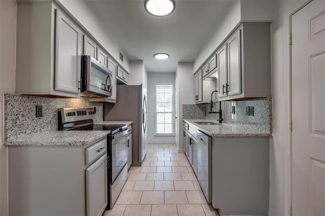a kitchen with stainless steel appliances granite countertop a stove a sink and a microwave