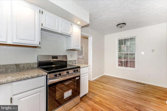 a kitchen with granite countertop wooden cabinets stove top oven and sink