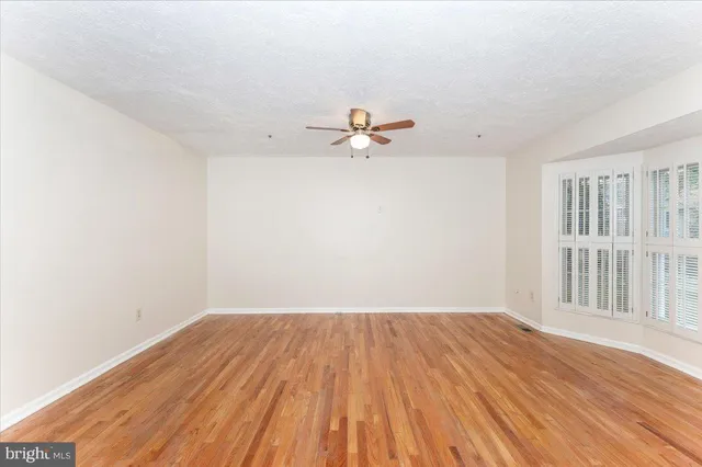 a view of a room with wooden floor and a ceiling fan
