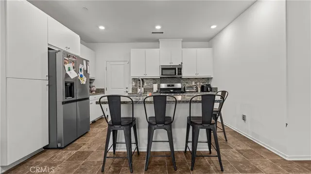 a kitchen with stainless steel appliances a dining table chairs microwave and sink