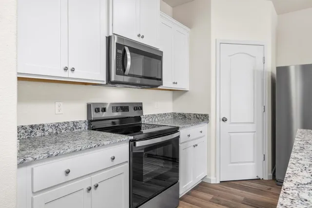 a kitchen with granite countertop white cabinets and stainless steel appliances