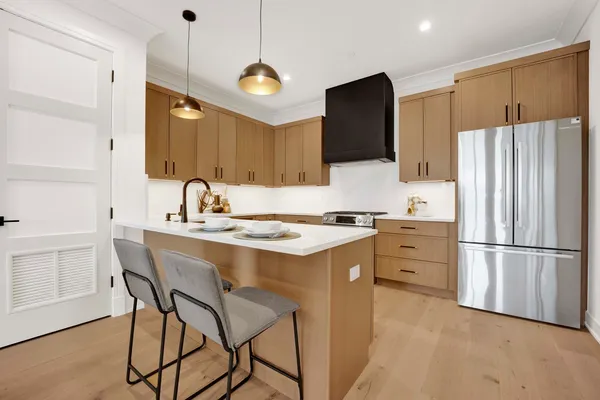 a kitchen with kitchen island a refrigerator a stove a sink and a oven with wooden floor