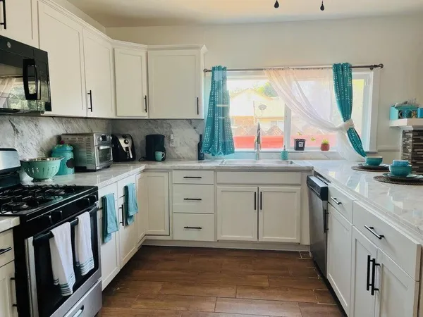 a kitchen with white cabinets and appliances