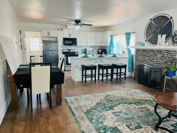 a view of dining room and kitchen with furniture wooden floor a rug and a fireplace