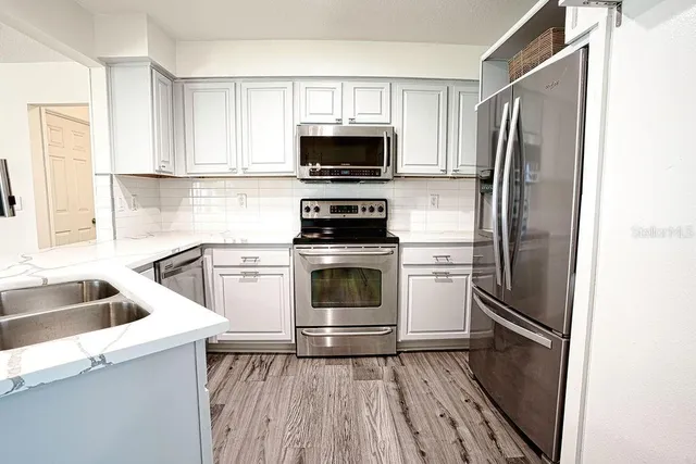 a kitchen with white cabinets and stainless steel appliances