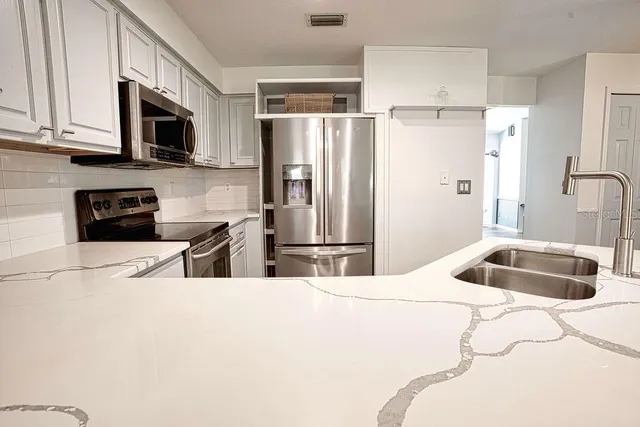 a kitchen with stainless steel appliances a refrigerator a sink a stove a microwave and cabinets