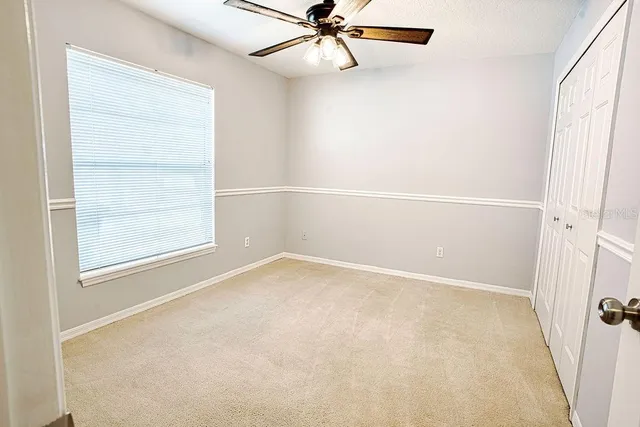 an empty room with a window and a fan
