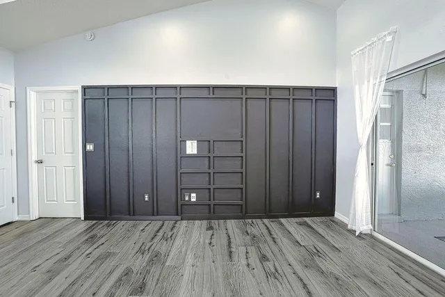 an empty room with wooden floor closet and windows