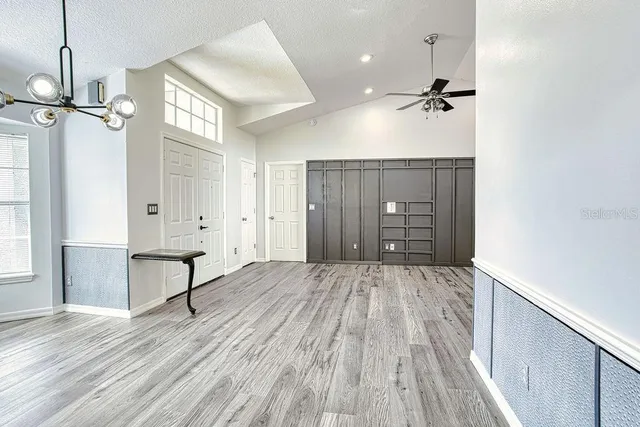 a view of empty room with wooden floor and fan