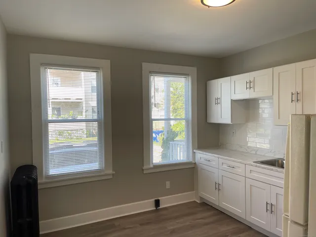 a kitchen with white cabinets and wooden floor