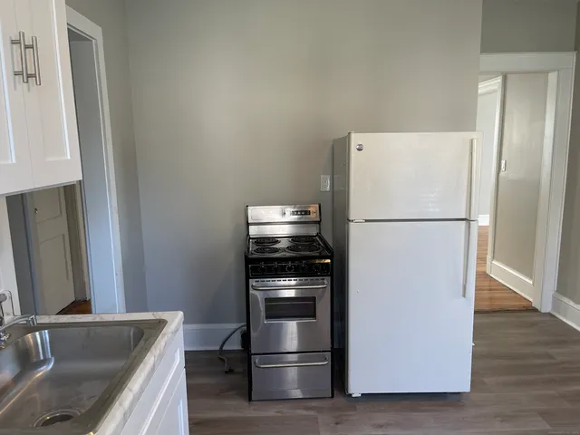 a kitchen with stainless steel appliances granite countertop a refrigerator sink and white cabinets