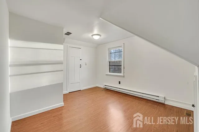 a view of empty room with window and wooden floor