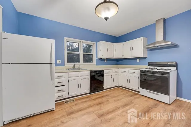 a kitchen with granite countertop a refrigerator stove and white cabinets