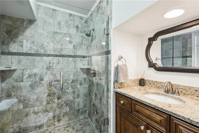 a bathroom with a granite countertop sink a mirror and shower