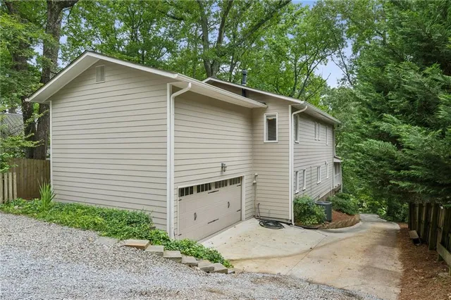 a white house with a small yard plants and large tree