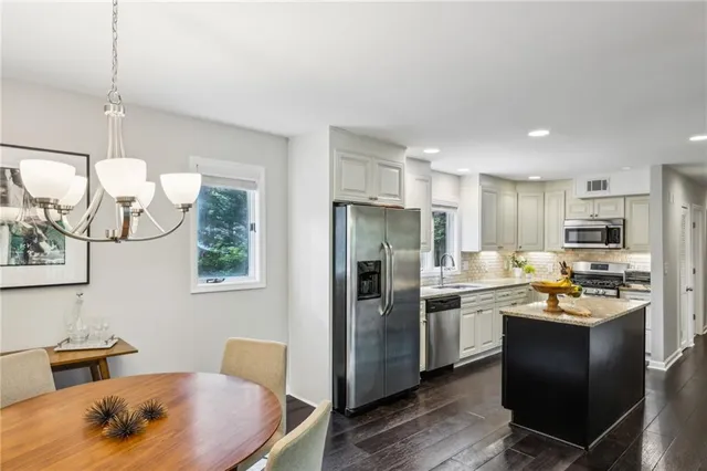 a kitchen with stainless steel appliances kitchen island granite countertop a sink refrigerator and cabinets