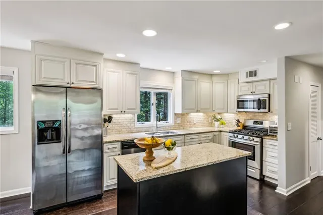 a kitchen with stainless steel appliances granite countertop a refrigerator a stove and a sink