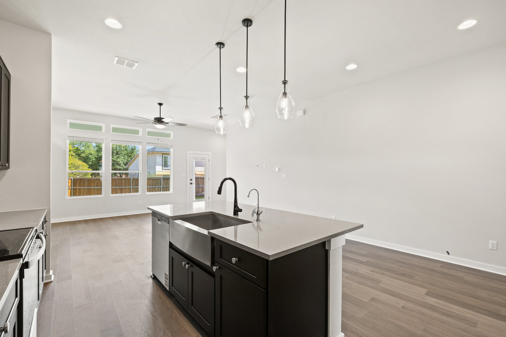 2205 Cento Walk Round Rock, TX 78664 - Photo 25 of 26 Kitchen featuring dark cabinetry, an island with sink, dark wood-type flooring, appliances with stainless steel finishes, and open floor plan