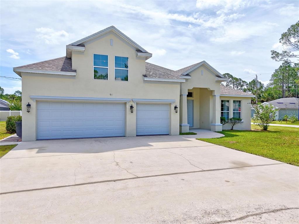 91 Sea Trail Palm Coast, FL 32164 - Photo 2 of 78 a front view of a house with a yard and garage