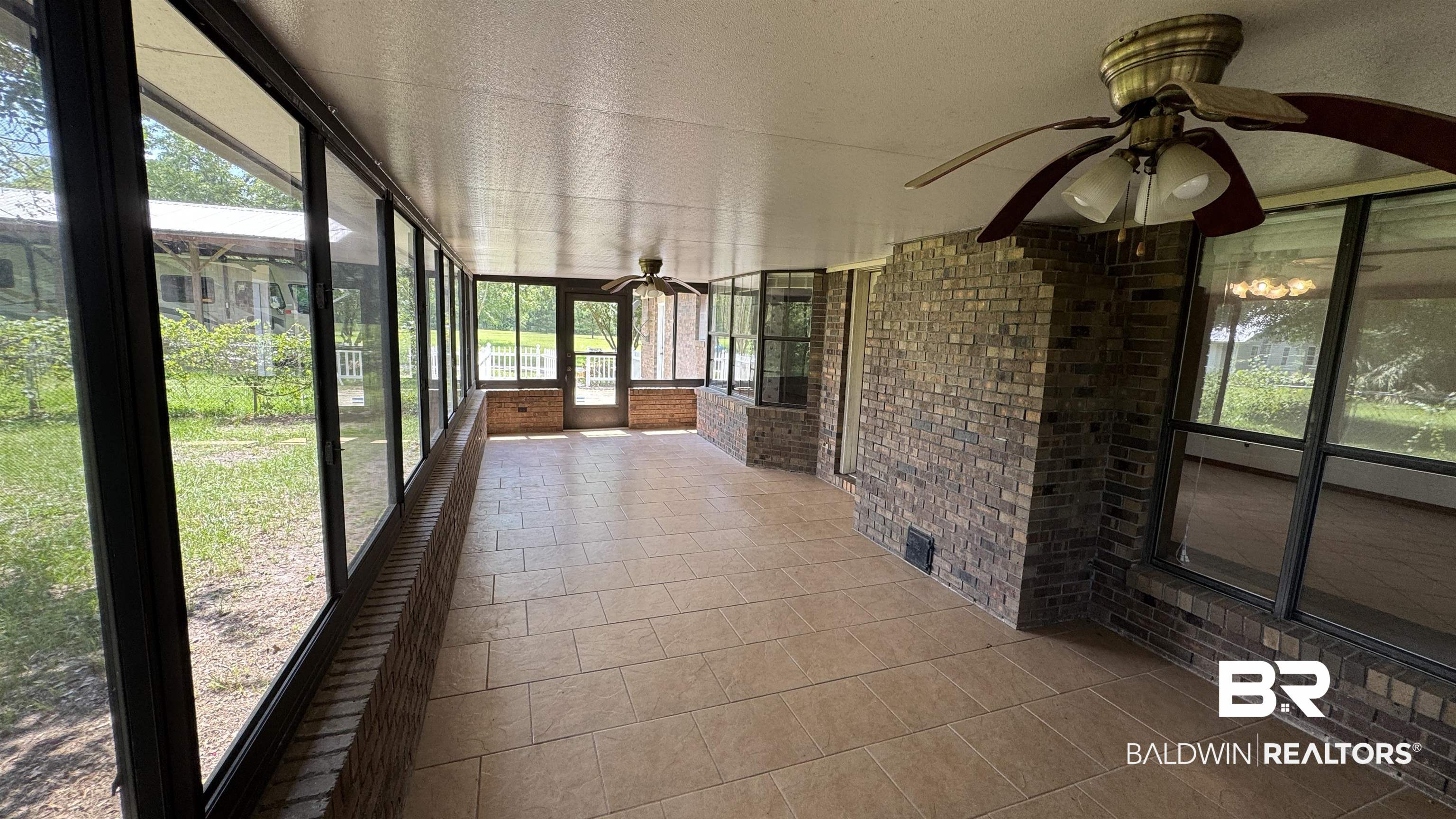 33370 Highway 98 Lillian, AL 36549 - Photo 42 of 58 Enclosed sunroom featuring extensive window panels, brick accent walls, tile flooring, and two ceiling fans with integrated lighting