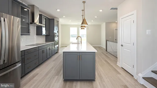 a large kitchen with stainless steel appliances a large counter top a stove a refrigerator and a cabinets