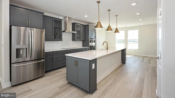 a large kitchen with stainless steel appliances kitchen island a large counter top a sink a refrigerator and a window