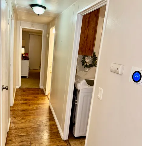 a view of a hallway with wooden floor and a bathroom