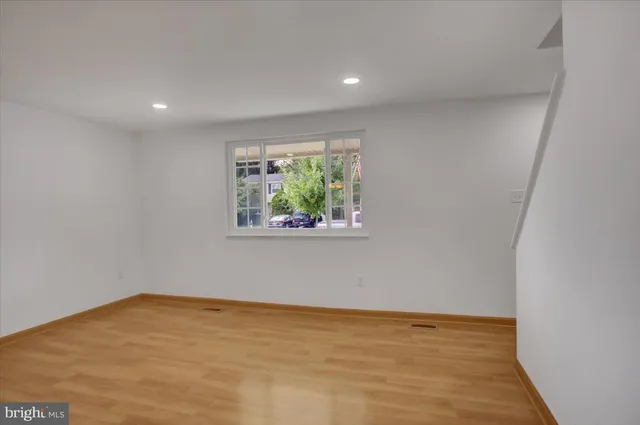 a view of an empty room with wooden floor and window