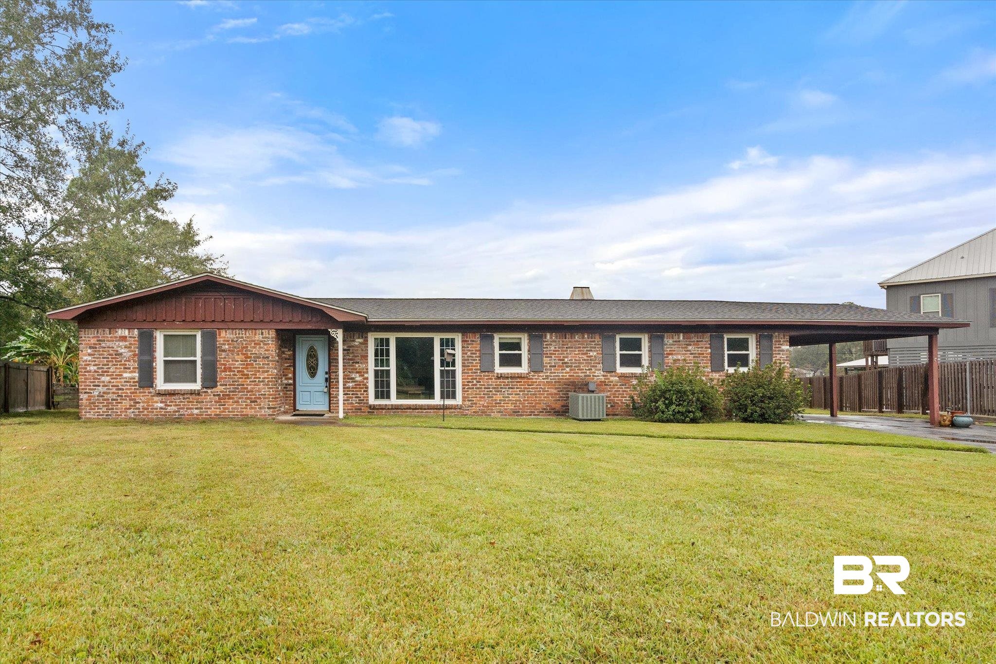 View of front of property featuring cooling unit, a front lawn, and a carport