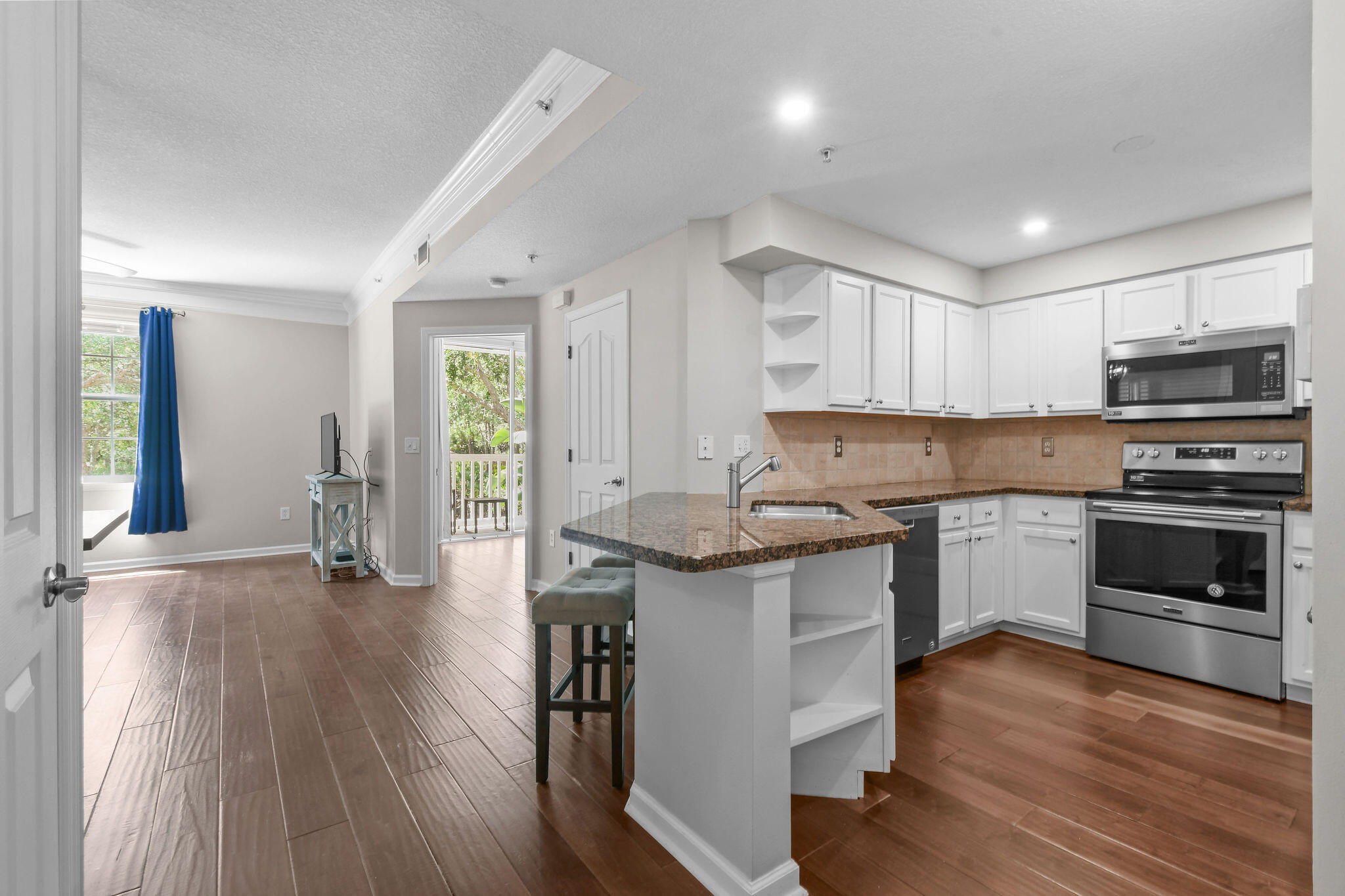 175 Galicia Way, Unit 211 Jupiter, FL 33458 - Photo 3 of 49 a kitchen with granite countertop a stove top oven a sink dishwasher a dining table and chairs with wooden floor