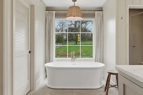 a white bath tub sitting in a bathroom next to a window