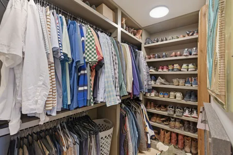a view of walk in closet with clothes and shoes