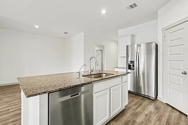 a kitchen with stainless steel appliances granite countertop a sink and a refrigerator