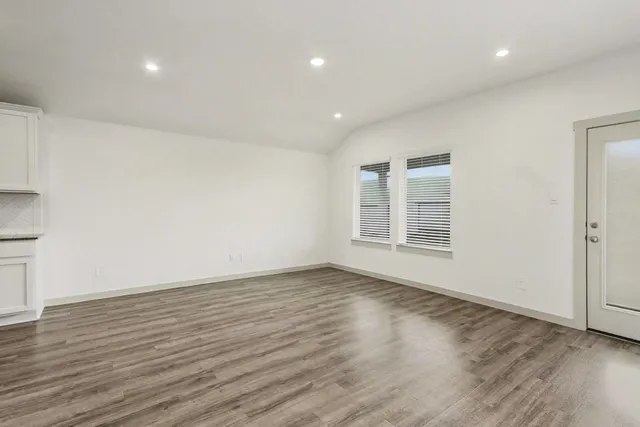 a view of an empty room with wooden floor and a window