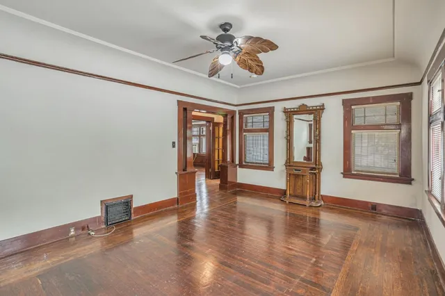 a view of an empty room with a window and wooden floor
