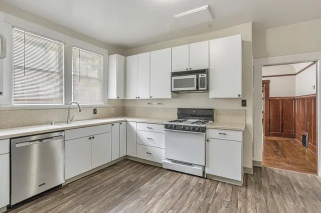 a kitchen with stainless steel appliances granite countertop a stove a sink and white cabinets