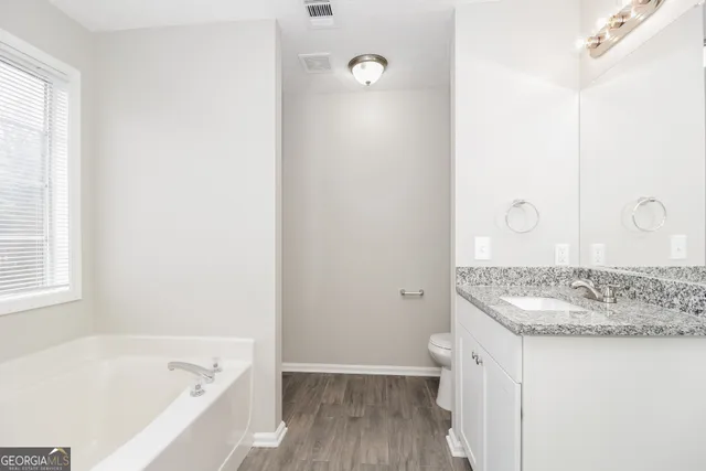a bathroom with a granite countertop sink a toilet and bathtub