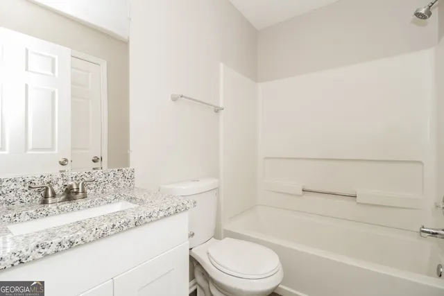 a bathroom with a granite countertop sink a toilet and bathtub