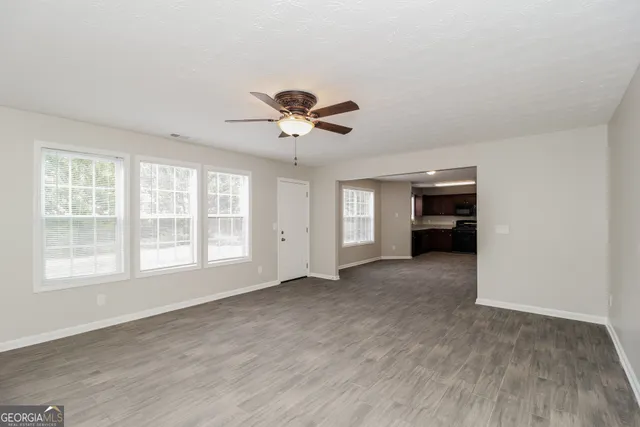 a view of an empty room with a window and a kitchen