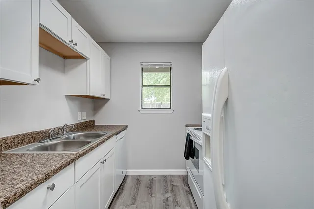 a kitchen with granite countertop a sink and a white cabinets