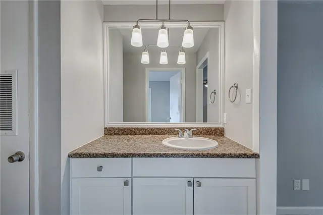 a bathroom with a granite countertop sink a mirror and a shower