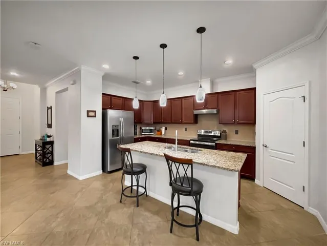 a kitchen with stainless steel appliances kitchen island granite countertop a table chairs and a refrigerator