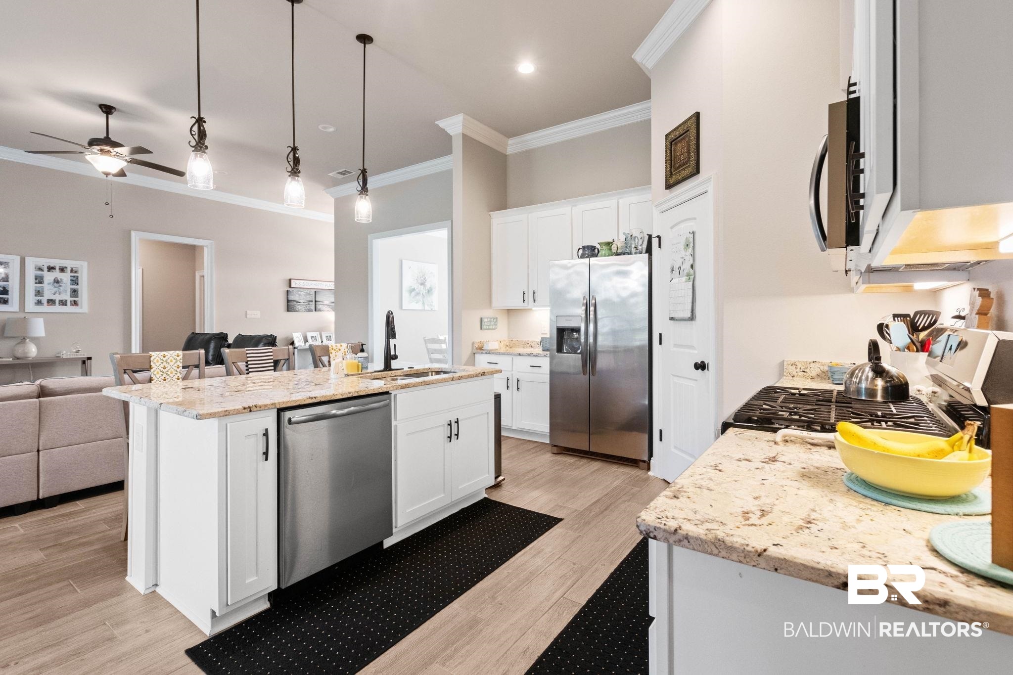 22244 Hibiscus Circle Foley, AL 36535 - Photo 26 of 51 Kitchen featuring white cabinetry, light granite countertops, stainless steel appliances, a center island with a built-in sink, and wood-finish flooring