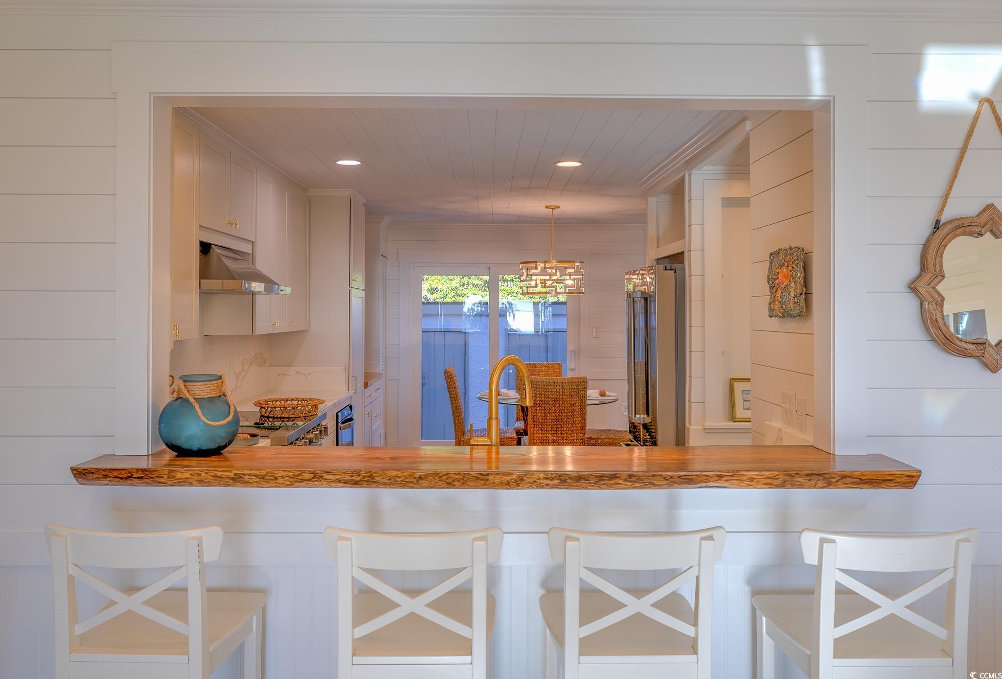 204 Bamboo Loop, Unit 202 Georgetown, SC 29440 - Photo 23 of 40 Kitchen featuring wooden counters, hanging light fixtures, a peninsula, wood walls, and stainless steel refrigerator