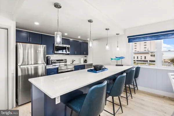 a kitchen with stainless steel appliances a table chairs refrigerator and microwave